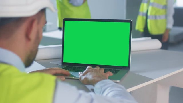Engineer using Laptop Computer with Green Screen inside Building Under Construction. Great for Mockup usage. Shot on RED Cinema Camera in 4K (UHD).