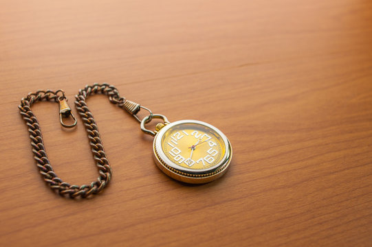 Pocket watch on wooden, close up, some blurred area.