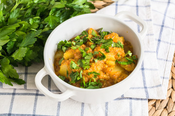 Stewed pumpkin and potatoes with parsley in white soucepan on th