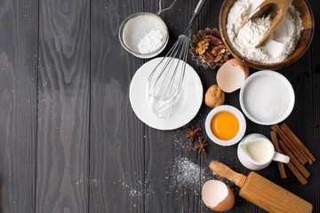 Baking ingredients for homemade pastry on dark rustic wooden background. Top view, flat lay style