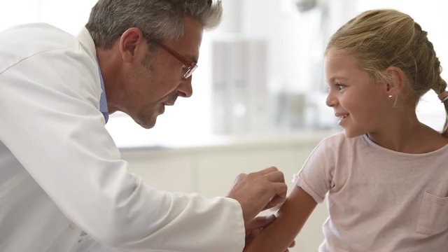 Doctor injecting vaccine to 5-year-old girl