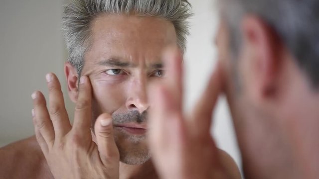 Mature man in front of mirror applying cream