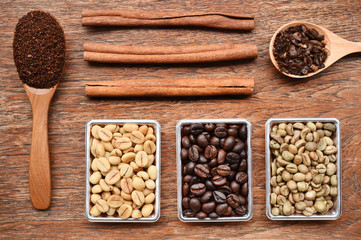 Coffee beans with ground coffee in wooden spoon and cinnamon 