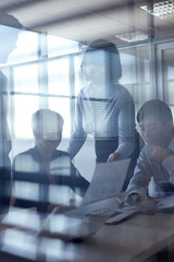 Working businesspeople viewed through glassy wall