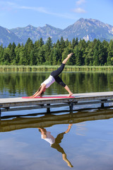 Fototapeta na wymiar Pilates-Übungen in der Morgensonne am See