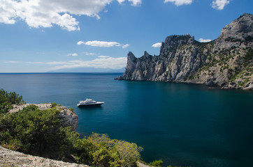 Fototapeta na wymiar Yacht in the sea on blue sky background. Top view of Blue Bay and the mountains on the Black sea coast. Royal Beach, Crimea