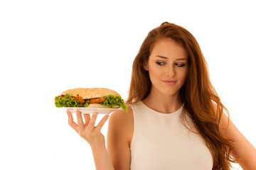 Unhealthy meal - happy young woman eats hamburger isolated over