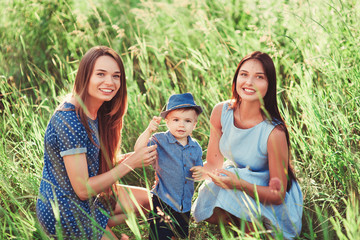 Beautiful happy family resting in nature. Two women - mom and aunt play with a boy in the Park....