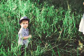 a little boy walks on the green lawn. The child plays outdoors. soft focus