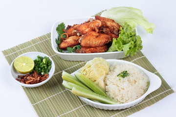 Sticky rice with fried chicken topped fried sliced red onion on bamboo and white. Side view.