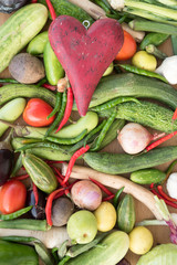 Wooden red heart on top of various fresh organic healthy vegetables 