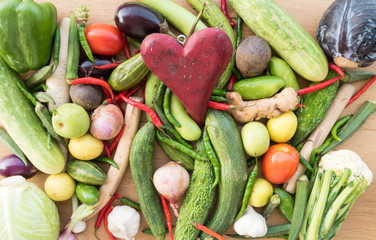 Wooden red heart on top of various fresh organic healthy vegetables 