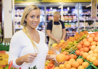 Female Customer Holding Orange In Supermarket