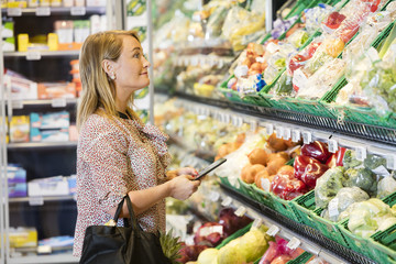 Customer Holding Digital Tablet While Looking At Vegetables