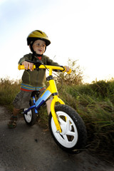 Baby boy riding on his first bike. Bike without pedals. Child learning to ride and balance on his two wheeler bike with no pedals.


