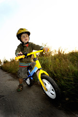 Baby boy riding on his first bike. Bike without pedals. Child learning to ride and balance on his two wheeler bike with no pedals.

