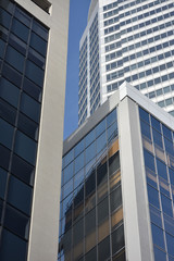 City downtown scene with three overlapping skyscrapers of various colours and patterns.