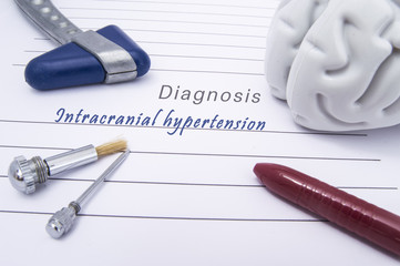 Figure of human brain, blue neurological reflex hammer, neurological needle and brush for test sensitivity and ballpoint pen lie on a paper form with a medical diagnosis of Intracranial hypertension