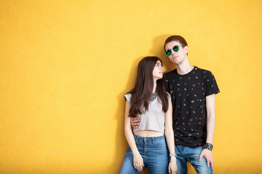 Young couple looking cool on yellow wall