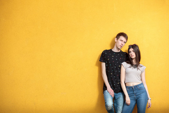 Cool couple looking in the camera on yellow wall