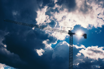 Obraz premium Silhouette of industrial construction crane with dramatic sky background. Details of industry
