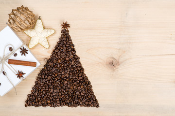 Christmas tree made from coffee beans and gift box on wooden background. Top view, copy space.Winter holidays concept.