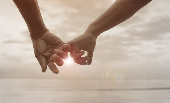 close up hand of senior couple hook each other's little finger together near seaside at the beach,light and flare effect added,filtered image,selective focus,love forever concept - Powered by Adobe