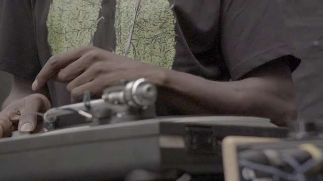 Black DJ hand spinning a vinyl on a turntable. 200 fps slow-motion, SLOG3, medium shot.