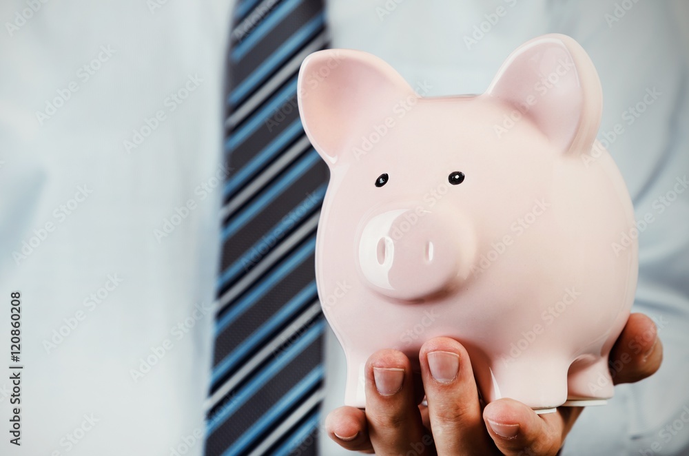 Wall mural Business man holding piggy bank in hand