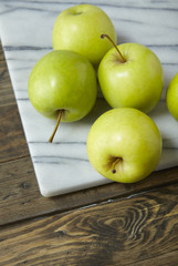 Green apples on a rustic wood and marble background forming a page border