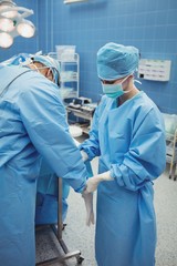 Nurse helping a surgeon in wearing surgical gloves