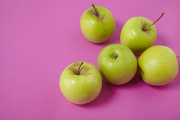 Green apples on a bright pink background forming a page border
