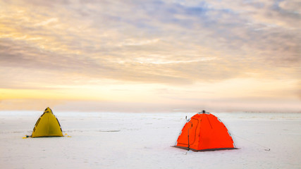 Bright tents camping of the expedition on the ice of the Northern territory. Wild adventure tours and trekking in the harsh winters of Northern nature. Courage and fortitude of traveler. North pole.