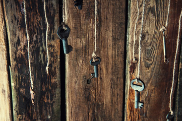 Many keys hanging on a string. Wooden background. Selective focus