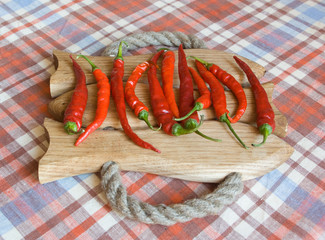 Eleven fresh red chili peppers on a handmade wooden board under a daylight - 120863435