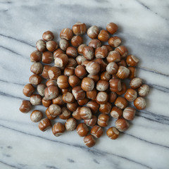 A pile of hazelnuts on a marble counter top background