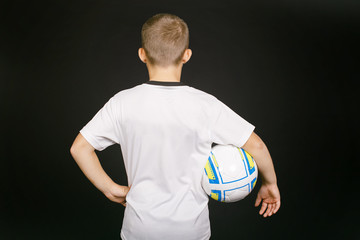 young football player with ball in hand. boy member of the football team. view from the back. empty space on white t-shirt for your text. isolated on black background. 