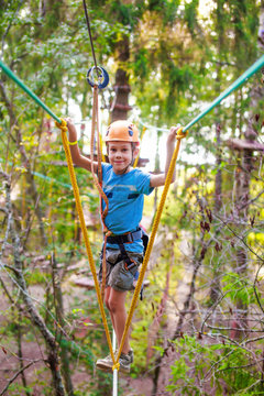 boy enjoys zip line. joyful child on a height in the high wire park. looking at camera