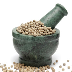 Organic White Pepper (Piper nigrum) on marble pestle and over white background.