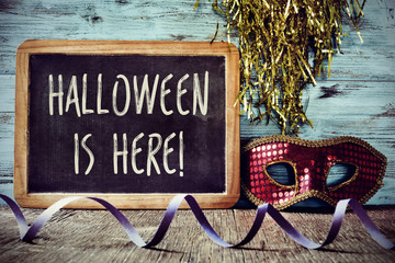 mask and text Halloween is here in a chalkboard