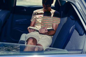 young man reading a book in a car