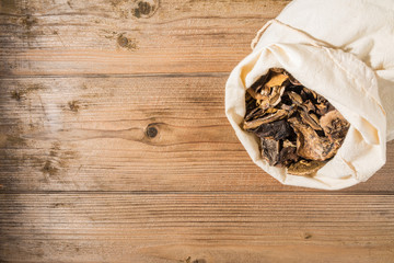 Dried mushrooms in a sack on a wooden table
