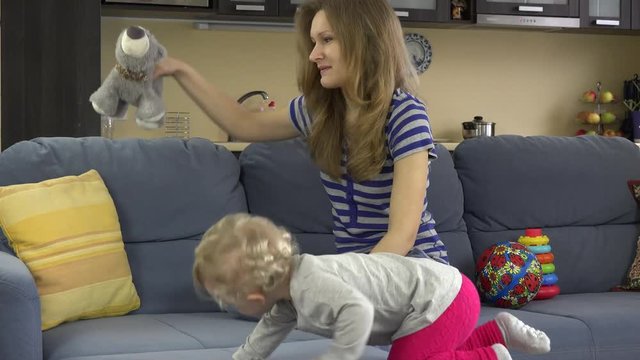 Babysitter woman have fun with baby girl on sofa at work.