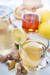 Ginger tea served with honey, lemon and mint on white table