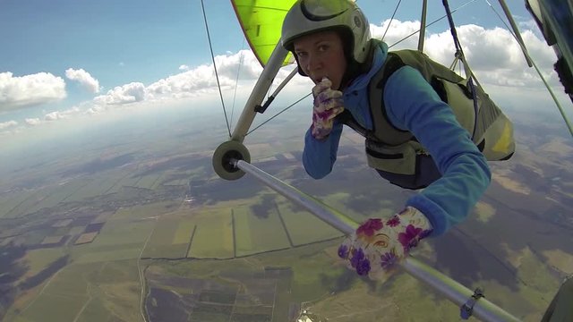 Woman paints her lips with lipstick in flight on a hang-glider