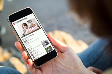 woman sitting in the street with vlog holding her smartphone