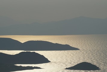 Sunset haze with flickering reflection between small islands in the sea - obrazy, fototapety, plakaty