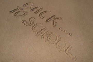 Back to school sign on the beach sand