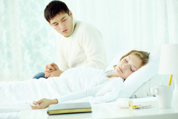 Fototapeta premium Man looking anxiously at his wife that fell asleep with fever