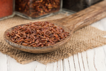 Brown rice in a wooden spoon and an old wooden table.